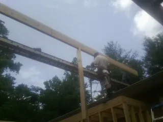 Carpenter setting a ridge beam over a new addition frame — Ice Dam Removal by Roofing Brothers in Hamptonville