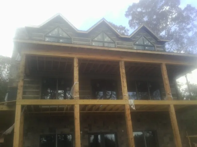 Dormers and porch framing on a large log home under construction — Roof Coating work by our crew in Hamptonville