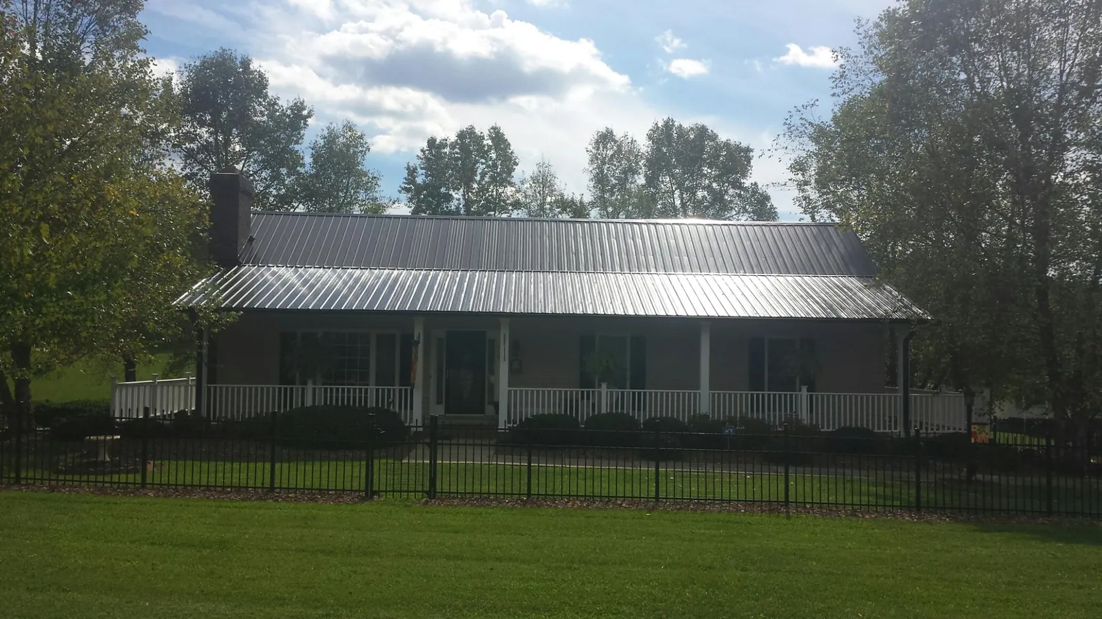 Gray metal roof on a brick ranch with a full width front porch — Gutter Guard Installation work by our crew in Hamptonville