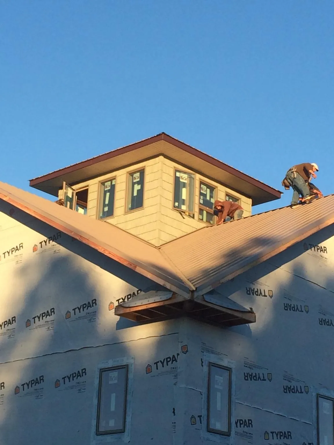 Roofers working around a rooftop cupola on a new metal roof at sunset — Roof Waterproofing in Hamptonville by Roofing Brothers